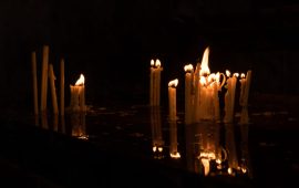 Several candles flame reflection in water in dark in armenian church