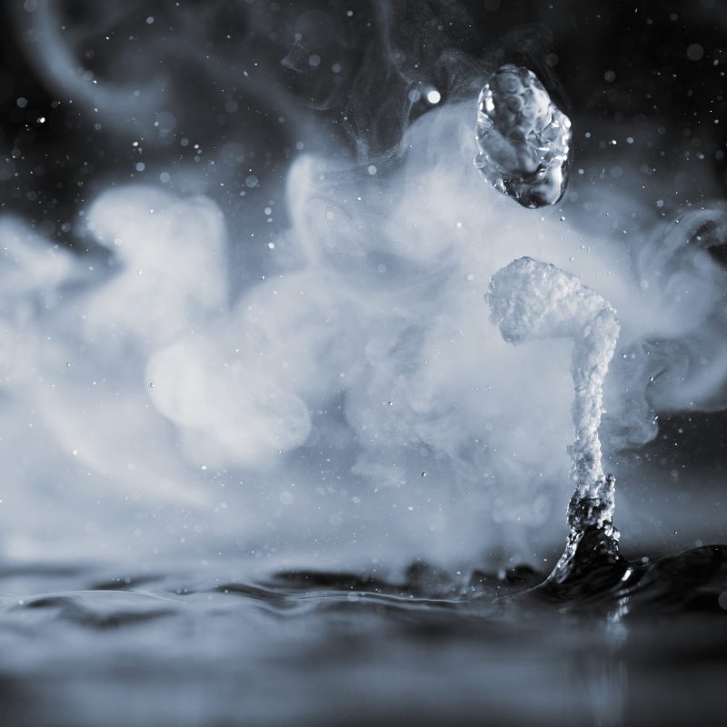 Boiling water splash with steam on black background close-up